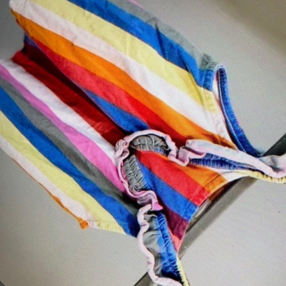 Features ruffled vibrant striped blouse